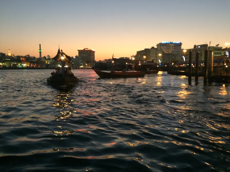 An abra on Dubai Creek at dusk with the Deira waterfront lit up